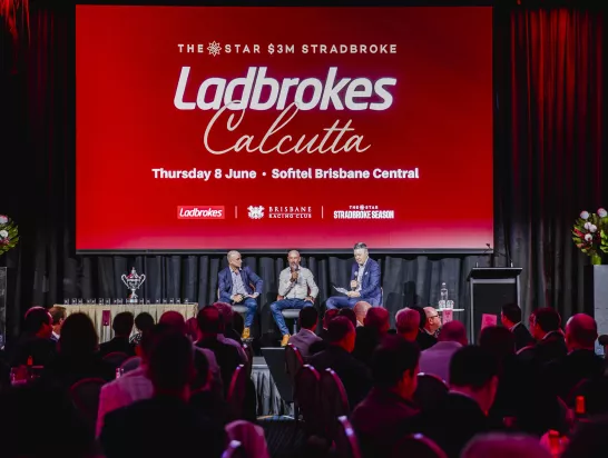 A panel of 3 men on stage during a Ladbrokes Calcutta event