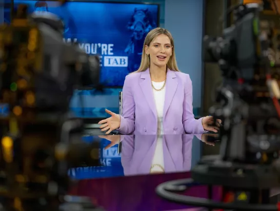 A female broadcaster talks to the camera in a studio